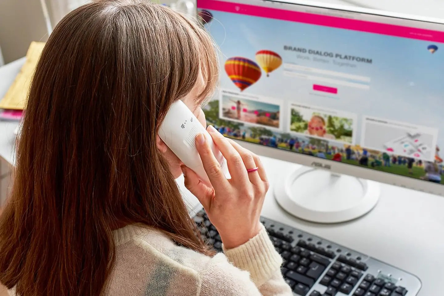 Eine Frau telefoniert vor eihrem PC