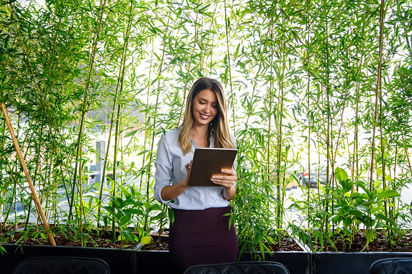 Woman checking data on tablet in front of green plants background
