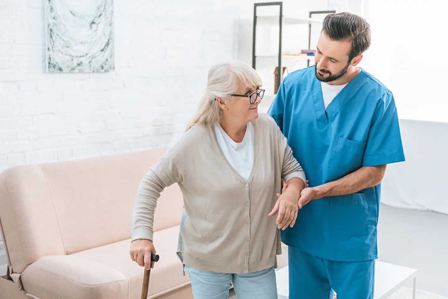 Male nurse supporting senior woman in clinic