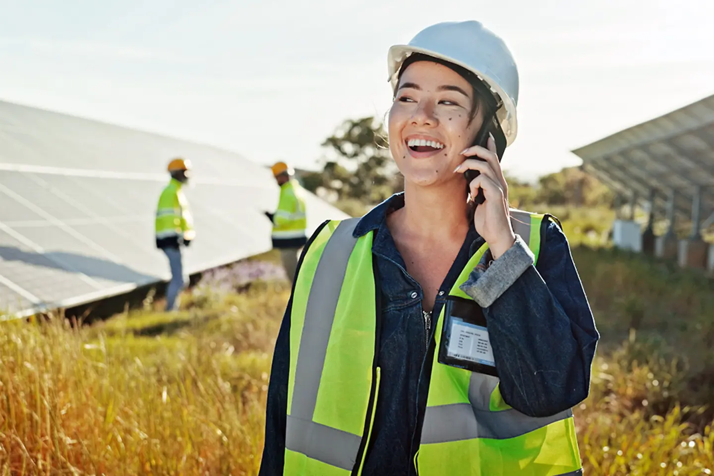 A female engineer makes a phone call outdoors for technical support.