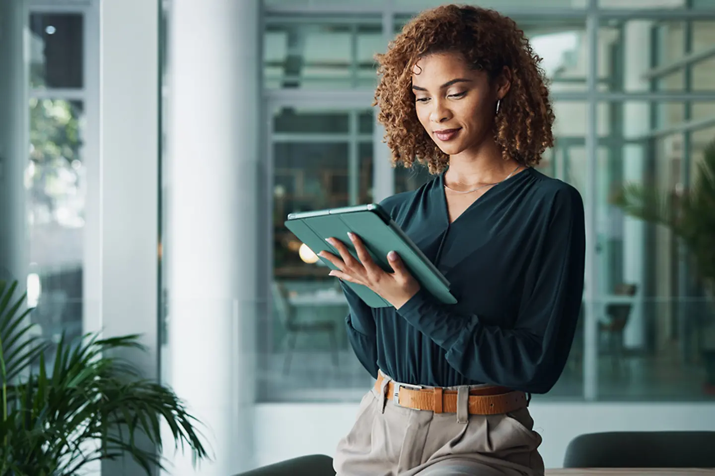 Female office worker in office accessing data on tablet