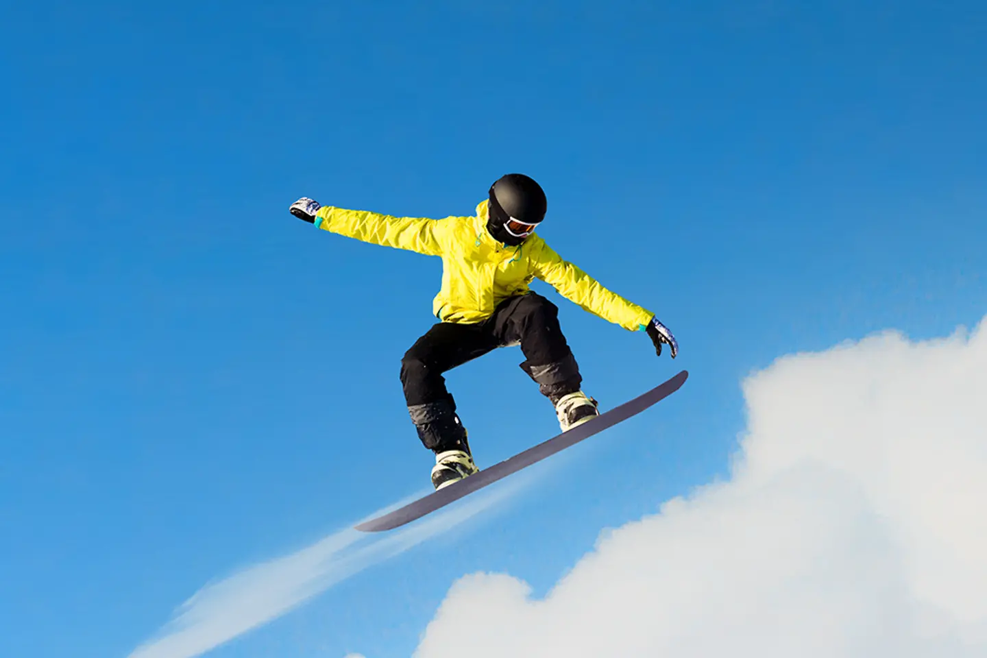 Snowboarder making jump with clouds in background