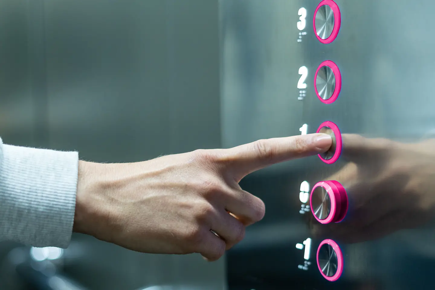 Person in an elevator pushing magenta button