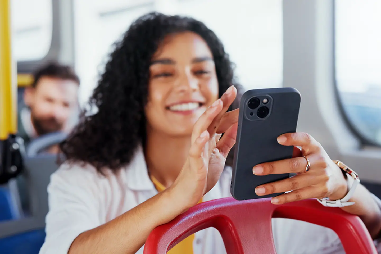 Eine Frau fährt mit dem Bus und tippt auf einem Mobiltelefon.