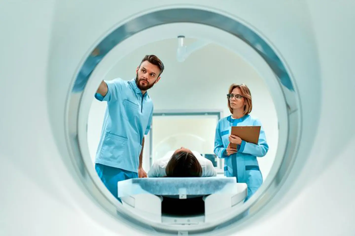 Two doctors monitor a patient entering a CT scanner.