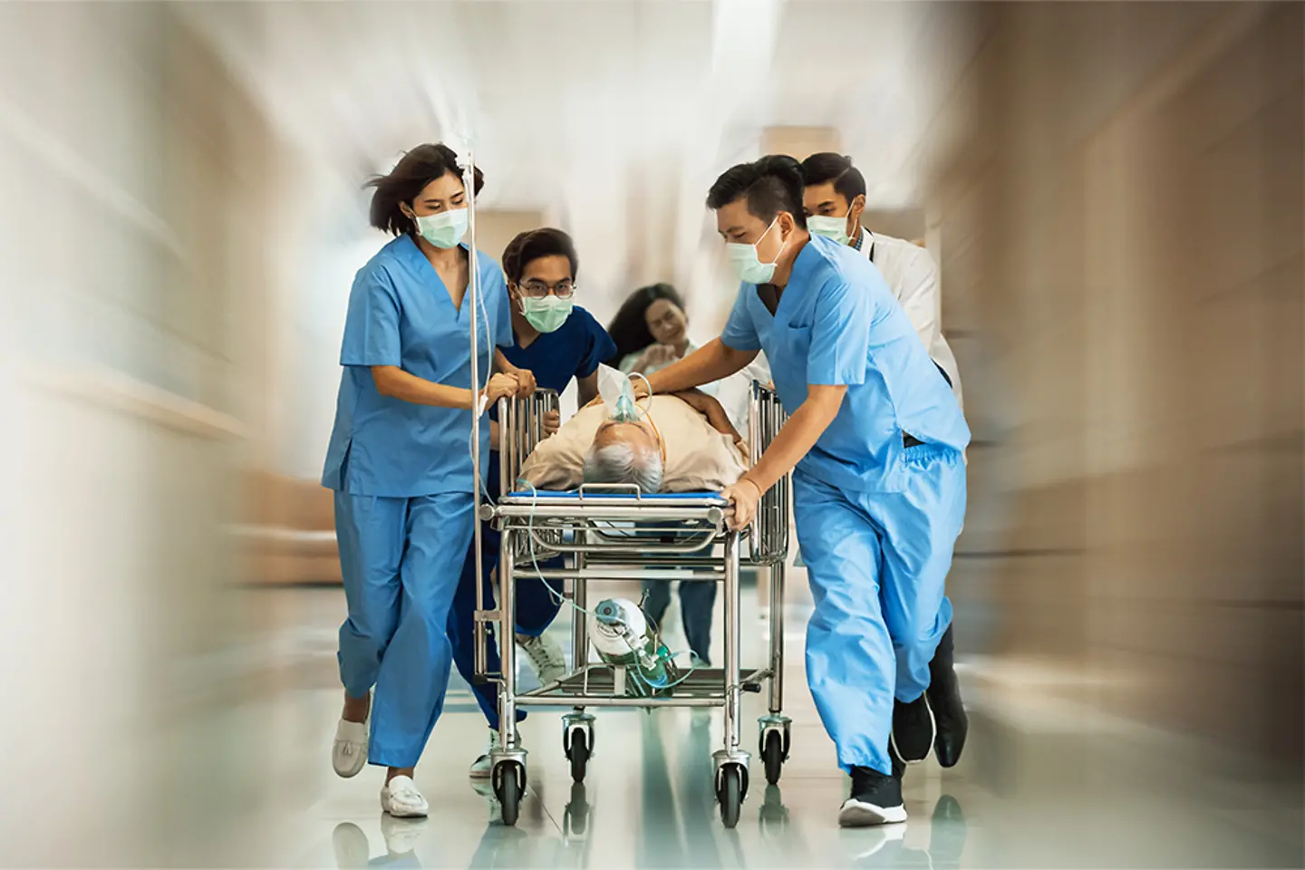 A team of doctors runs with a patient on a stretcher in the emergency room