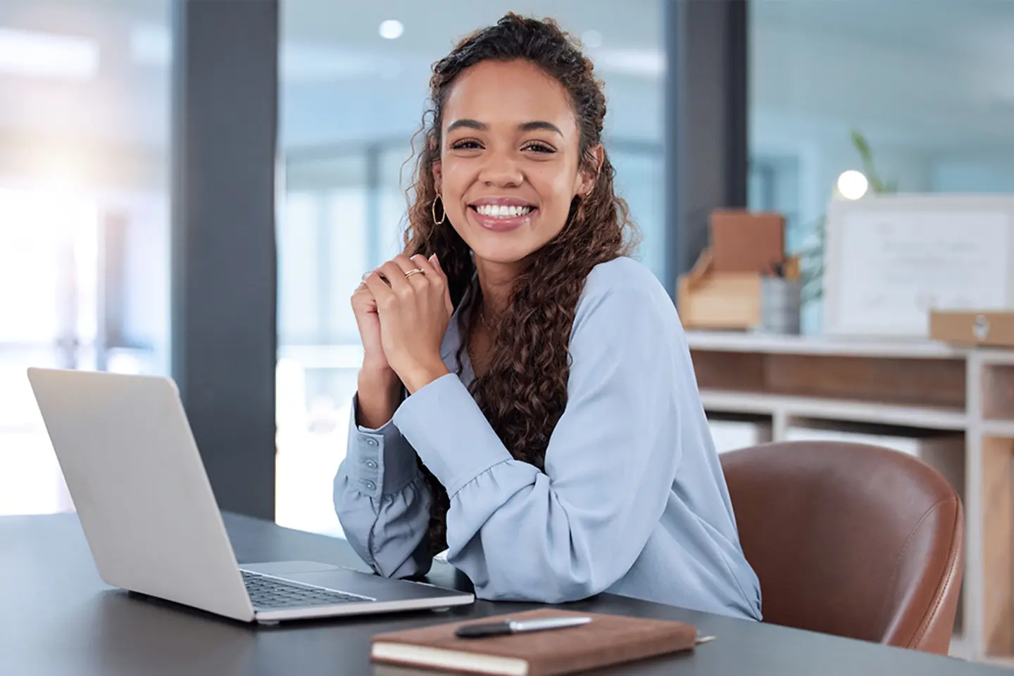 Funcionária de escritório sorrindo em frente a um laptop