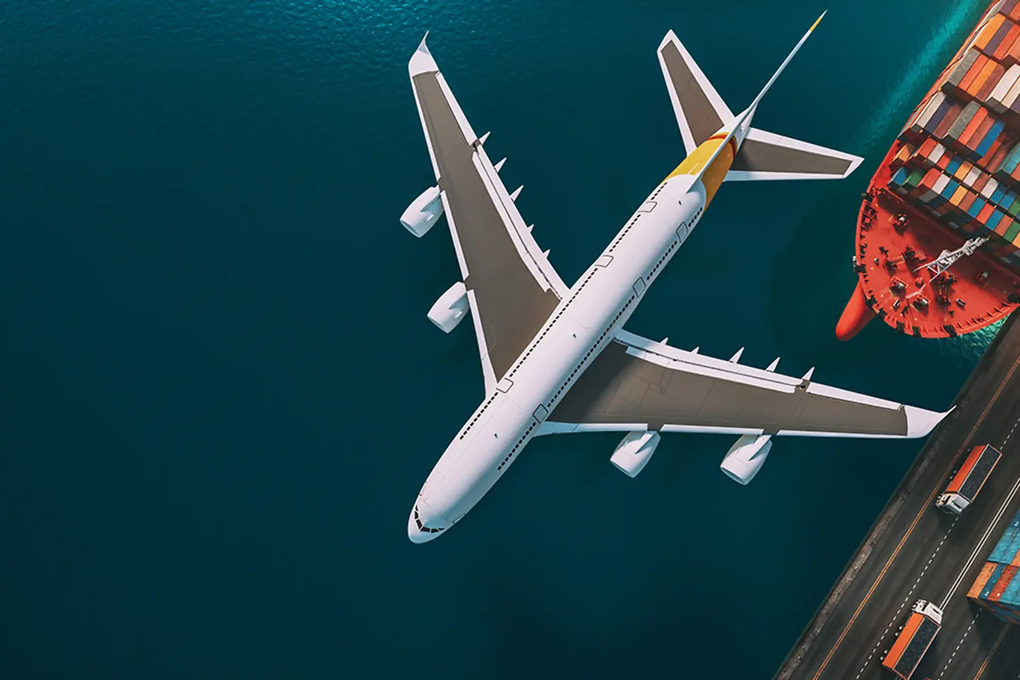 Plane, cargo ship and trucks in a port.