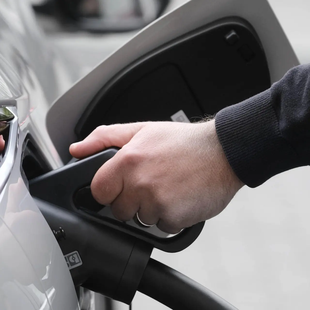 Eine Hand hält ein Ladekabel, das in einem Auto steckt