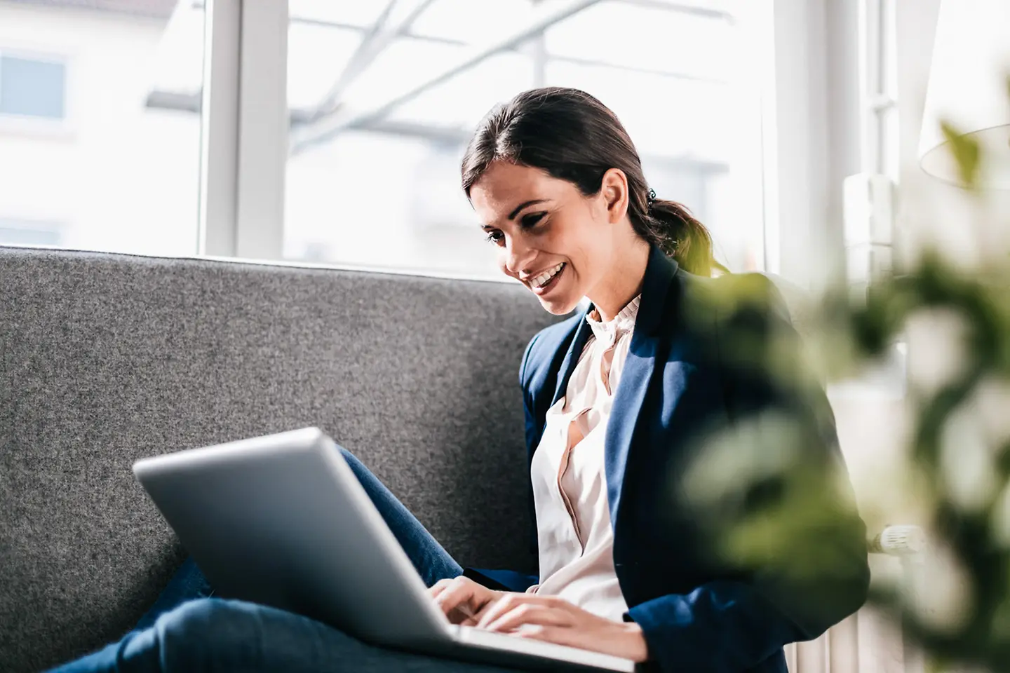 Mujer sonriente sentada con un laptop en su regazo