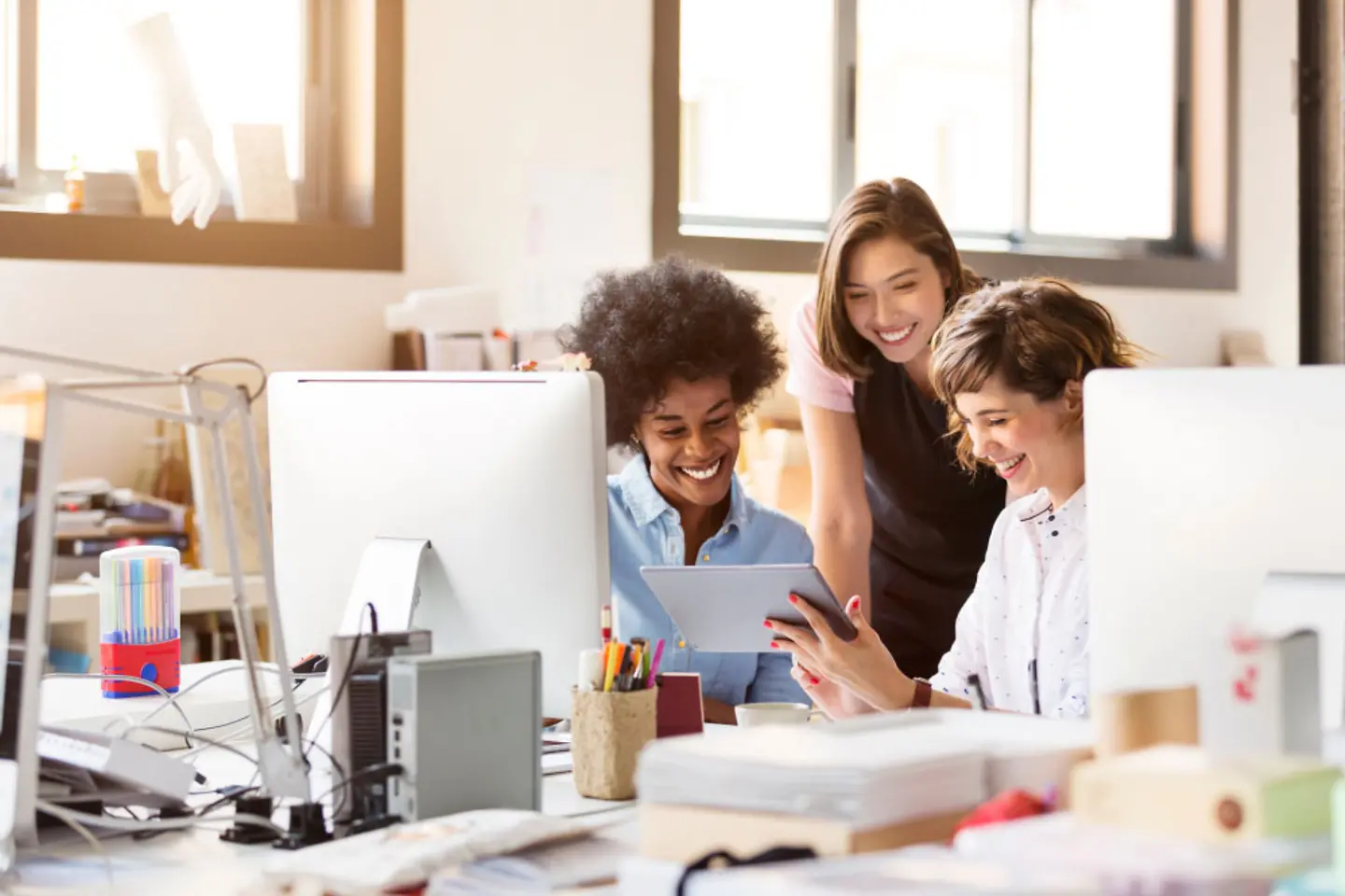 Eine Gruppe Frauen bespricht im Büro etwas auf einem Tablet