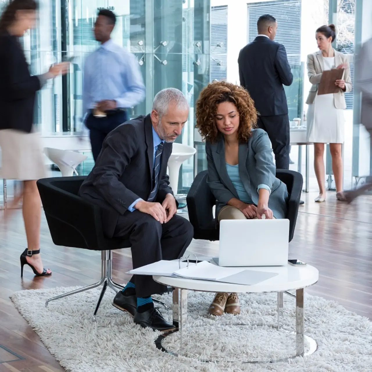 Businesspeople discussing data transformation at a table with a laptop on it